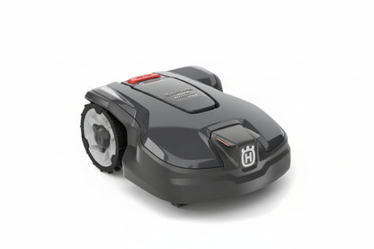 Husqvarna robotic lawnmower in dark gray and black with a red button and white Husqvarna logo, shown on a light gray background.