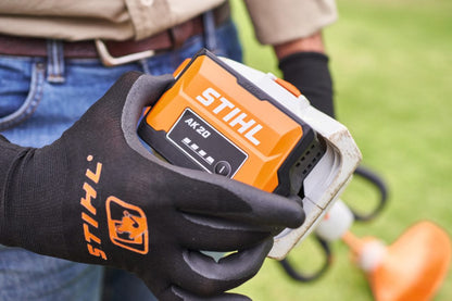 Person holding a STIHL battery AK20 & power tool with grass in the background