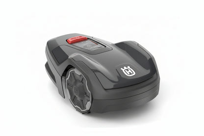 A Husqvarna robotic lawnmower in dark gray with a red button and a white Husqvarna logo on the front, shown on a light gray background.