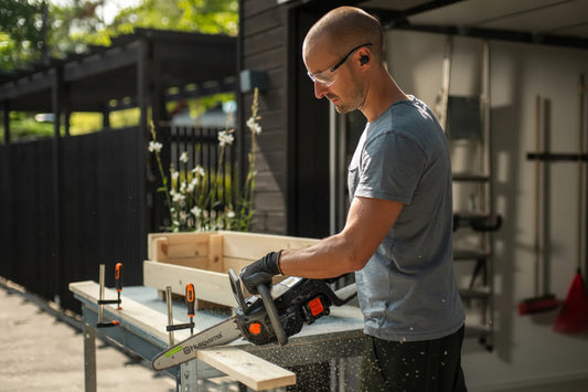 Man using a chainsaw on a wooden crate outdoors